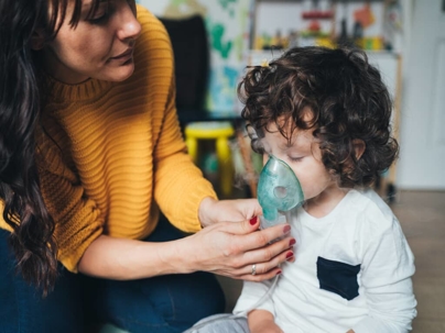 a woman helping her child with a breathing device